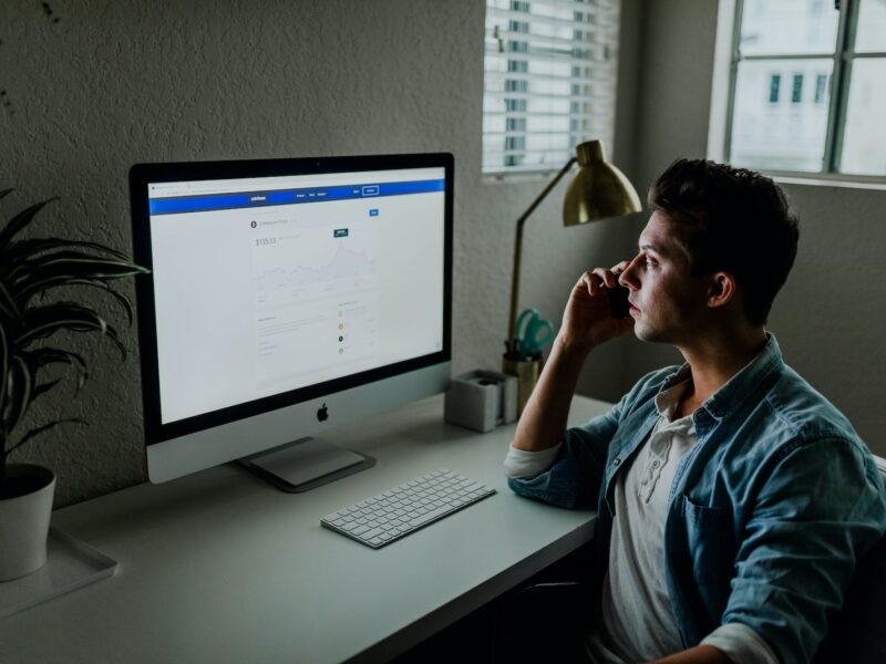 man in blue denim jacket facing turned on monitor