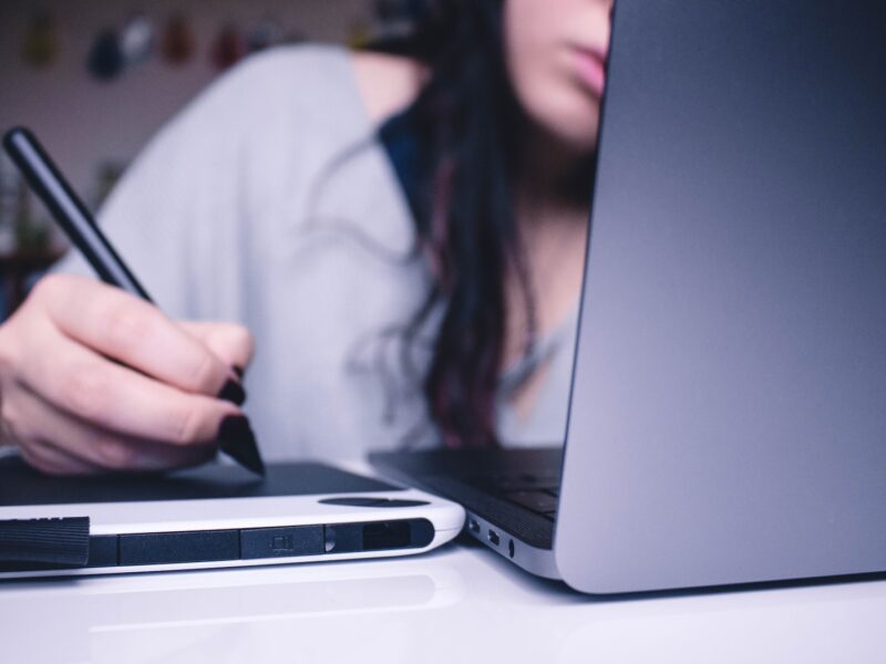 woman using drawing pad while sitting in front of laptop